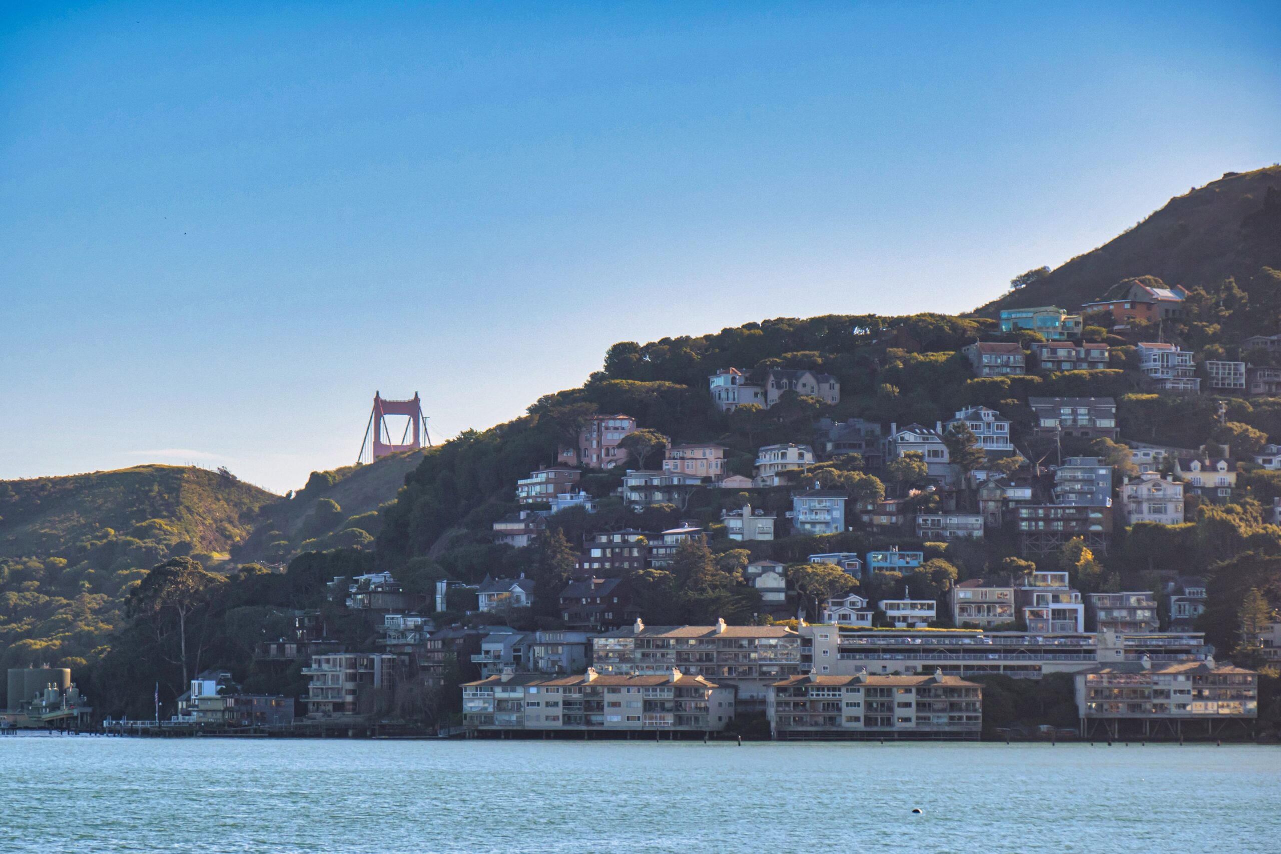 View of the hillside in Sausalito, CA, with the Golden Gate Bridge poking out in the distance.