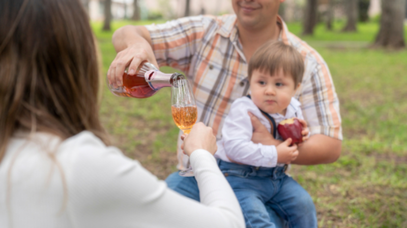 Selective focus on a glass of wine being poured by a father during a picnic, capturing a family-friendly private wine tasting experience at a winery with loved ones gathered outdoors.